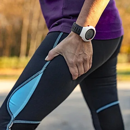 A runner grasping her leg in pain, indicating sciatica pain
