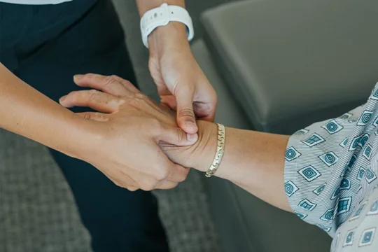 Dr. Emily Ronduen Bautista massaging and adjusting a patient's hand and wrist for carpal tunnel relief