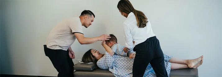 Chiropractor Rancho Cucamonga CA Emily Ronduen Bautista Dr. Emily Ronduen Bautista adjusting a baby while the child's parents smile