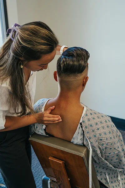 Chiropractor Rancho Cucamonga CA Emily Ronduen Bautista Dr. Emily Ronduen Bautista examining and adjusting a patient's neck and back while the patient is seated