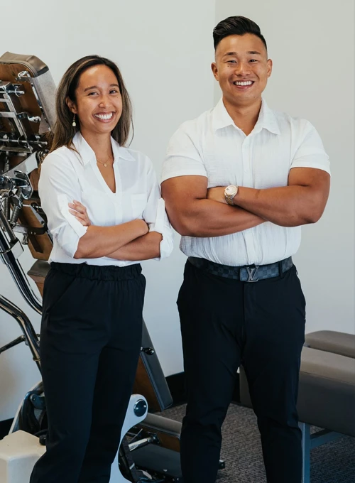 A photo of Dr. Emily Ronduen Bautista & Dr. Wilson Luu standing in an adjustment room at Structural Foundation Chiropractic